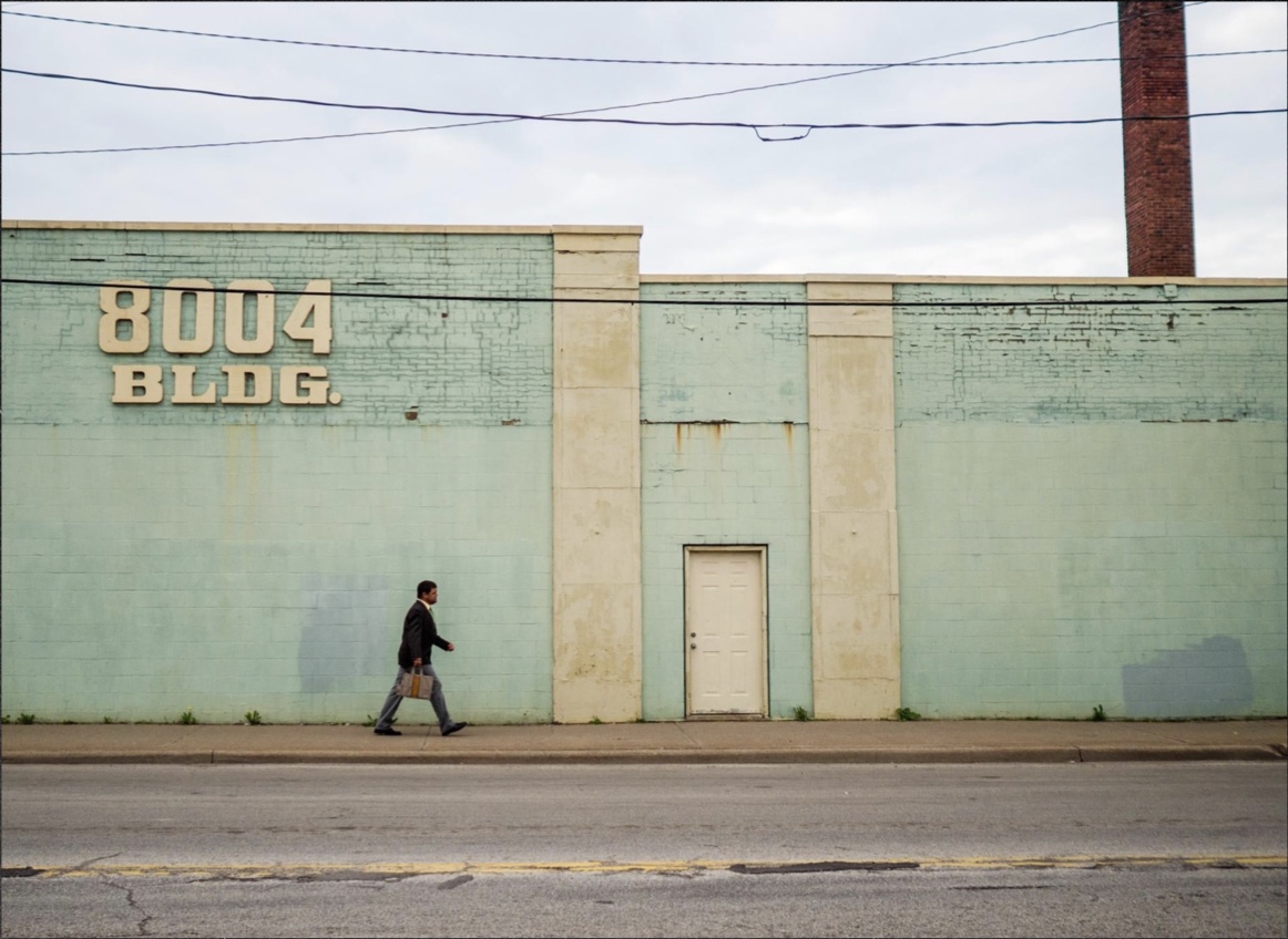 man-with-briefcase-walking-by-blue-building